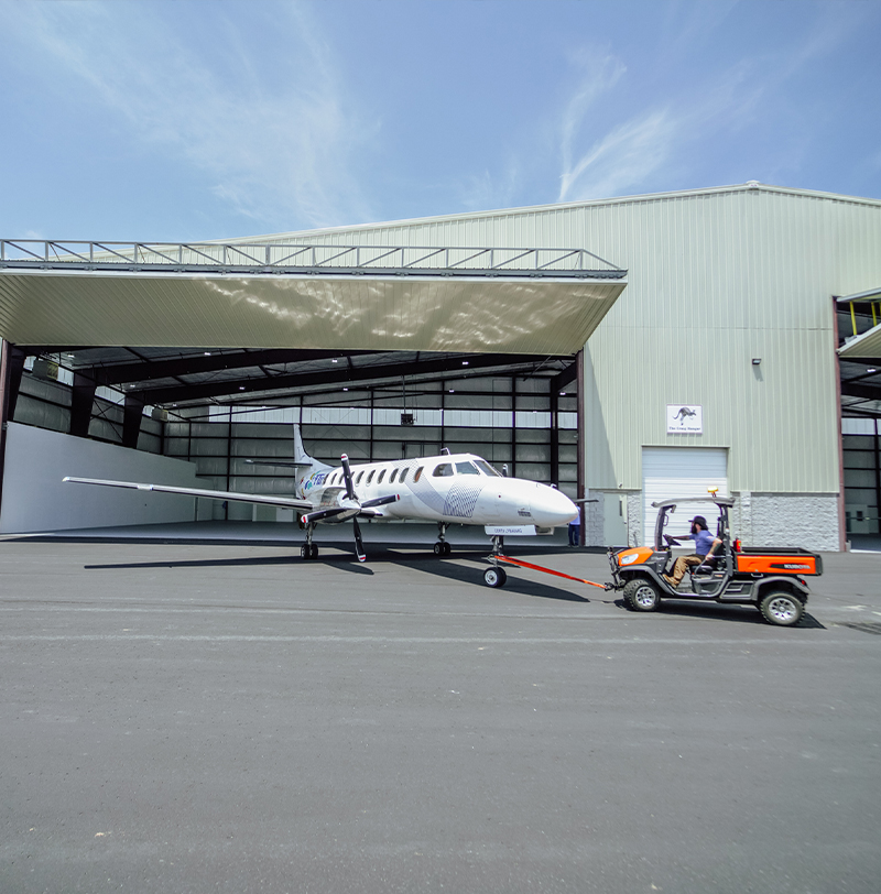 Image of a service technician pulling a medium sized plane out of a hangar.
