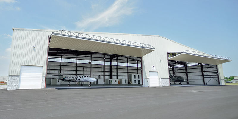 Image of a large hanger that houses a medium sized plane on one side and a jet on the other side.