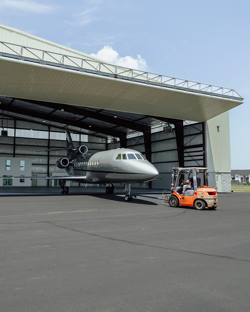 Image of a service technician pulling an aircraft out of a hangar.