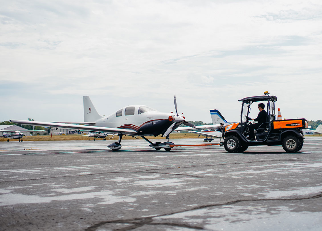 Image of a service technician towing a small aircraft.